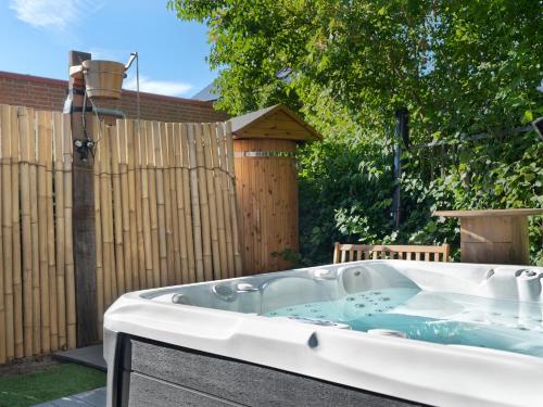 a hot tub in a yard next to a fence at Koraal - Comfortabele kamer bij B&B Gezond aan Zee - Toegang Wellnesstuin meerprijs in Ouddorp