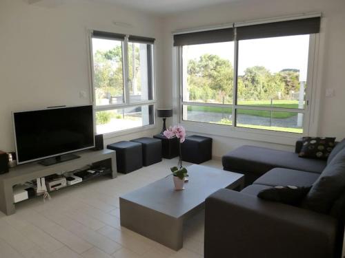 un salon avec un canapé et une télévision dans l'établissement Maison contemporaine vue mer et sauna, à Plouézec