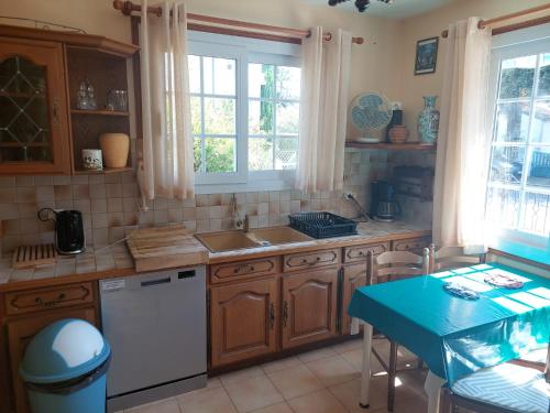 une cuisine avec des placards en bois et une table bleue dans l'établissement La Sirène Escapade en famille ou entre amis Maison lumineuse avec extérieur privé à 5 min de la plage Confort et convivialité assurés, à Saint-Trojan-les-Bains