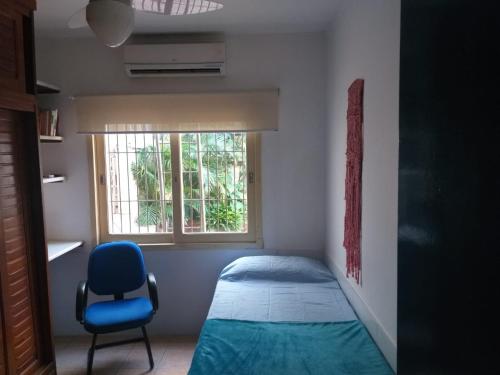 a small bedroom with a bed and a blue chair at casa das flores in Canoas