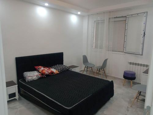 Un dormitorio con una cama negra y sillas. en Bel Appartement meublé à Bordj El-Kiffane, en Stamboul