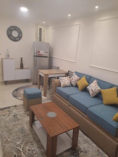 Una sala de estar con un sofá azul y una mesa. en شارع سوريا, en Alejandría