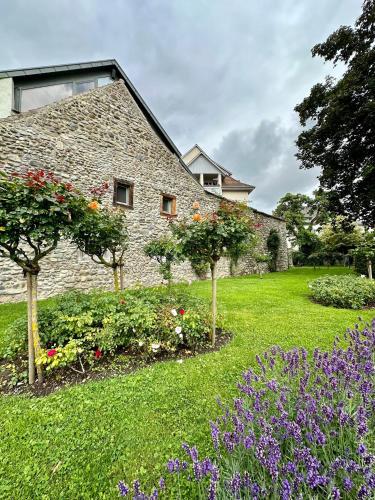 a stone house with trees and flowers in a yard at Ferienwohnung Stadtgarten in Radolfzell am Bodensee