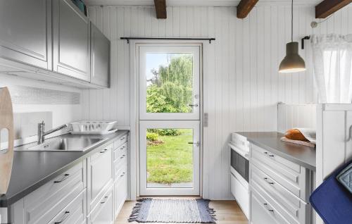 a kitchen with white cabinets and a door with a window at Amazing Home In Stege With Kitchen in Stege