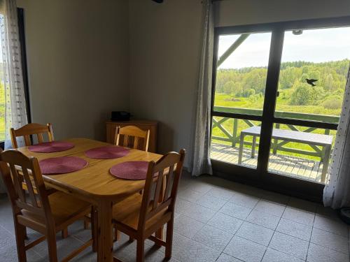 a dining room table with chairs and a large window at Żurawia Łąka in Bytów