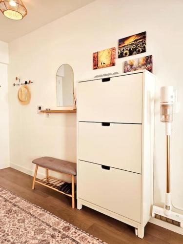 une commode blanche et un tabouret dans une pièce dans l'établissement Chic appartement en plein Paris, à Paris