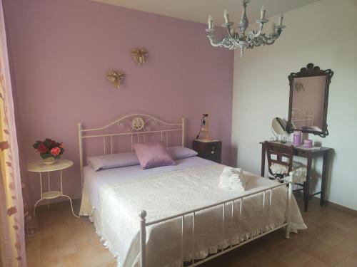 Un dormitorio con una cama con paredes moradas y una lámpara de araña. en La Casa del Duca, en Montalto delle Marche