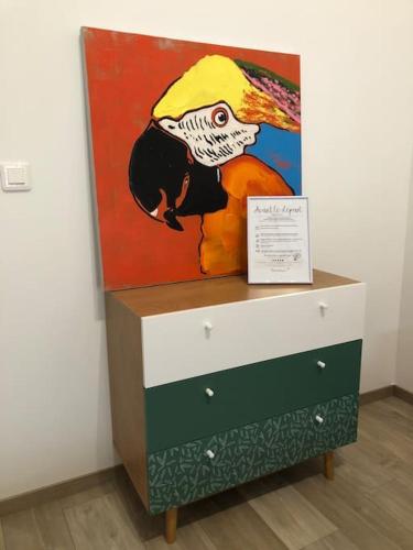 a painting of a parrot on a dresser in a room at L'IMPASSE, T2 neuf et bien équipé, plein coeur de Maincy in Maincy