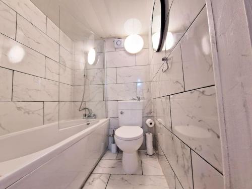 a white bathroom with a toilet and a tub and a sink at Charming 4 bedroom house in Nottingham -Entire House in Stapleford