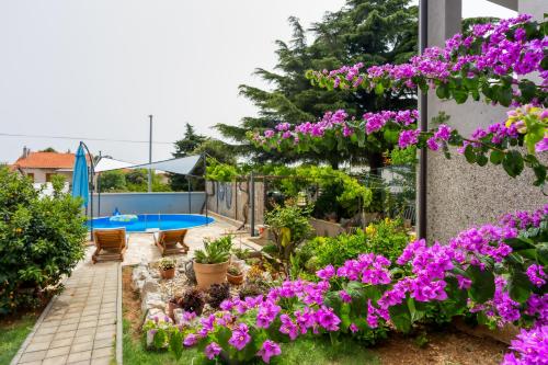 a garden with purple flowers and a swimming pool at Pool & Garden Apartment Bakija - Happy Rentals in Pakoštane