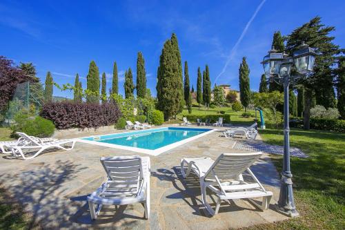 a group of chairs sitting around a swimming pool at Villa La Chiesina - Happy Rentals in Arcidosso