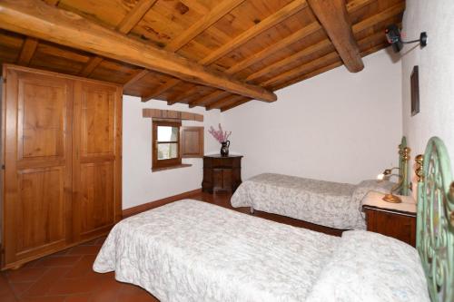 two beds in a room with wooden ceilings at Villa La Chiesina - Happy Rentals in Arcidosso