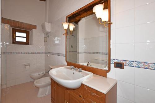 a bathroom with a sink and a toilet and a mirror at Villa La Chiesina - Happy Rentals in Arcidosso