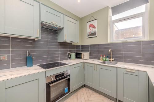 a kitchen with white cabinets and a window at 2 Bedroom Flat Next To Brighton Beach in Brighton & Hove