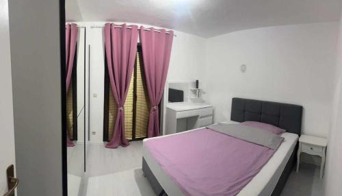 a bedroom with a purple bed and pink curtains at Apartment Alisha in Cazin