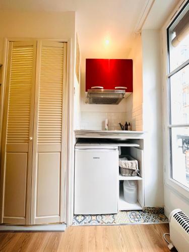 Elle comprend une petite cuisine équipée d'un réfrigérateur blanc et de placards rouges. dans l'établissement Studio Montmartre, à Paris