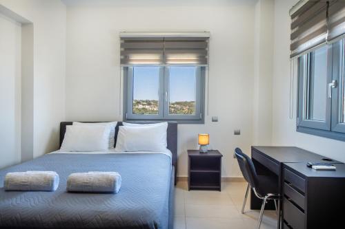 a bedroom with a bed and a desk and windows at Dias Luxury Villa in Koskinou
