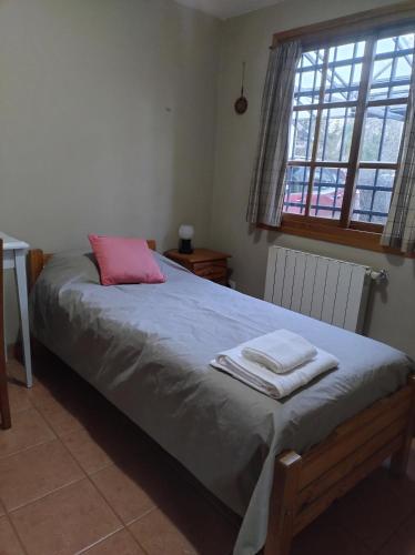 a bedroom with a bed with a pink pillow at Casa de Silvina in El Bolsón