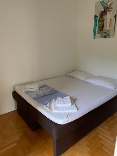 un letto in una stanza con lenzuola bianche sopra di Zara Apartman a Herceg-Novi