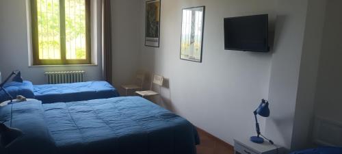 a bedroom with two beds and a television on the wall at Villa Tre Laghi Vista Paradiso Piscina acqua salata provincia Perugia conf Toscana 22 posti in Castiglione del Lago