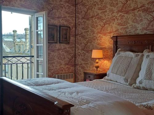 une chambre avec un grand lit et une fenêtre dans l'établissement Place de la Bastide, à Sainte-Foy-la-Grande