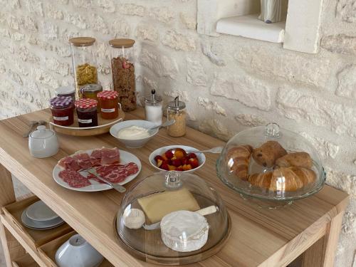a wooden table with various food items on it at Les gîtes des Lauriers roses Chambre privée Île d Aix in Geay