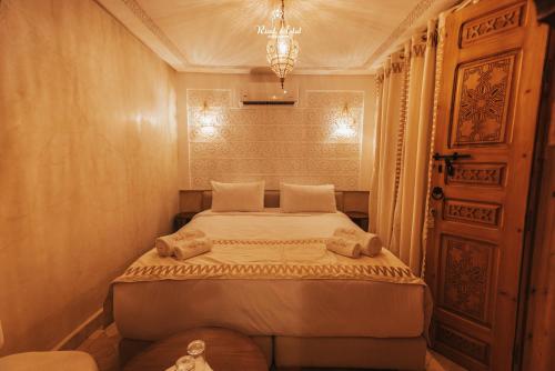 a bedroom with a large bed with a chandelier at Riad Aslal in Marrakech