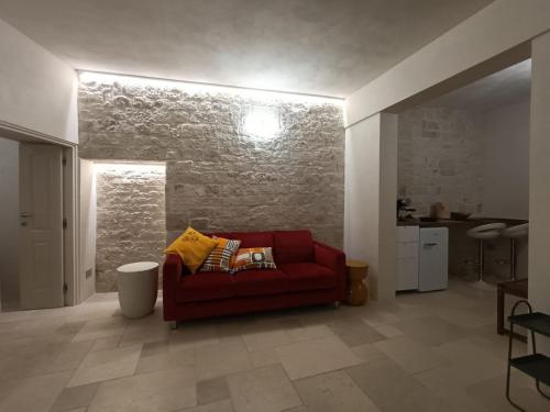 a red couch in a living room with a brick wall at Montesanto 60 Suite & Relax Alberobello in Alberobello