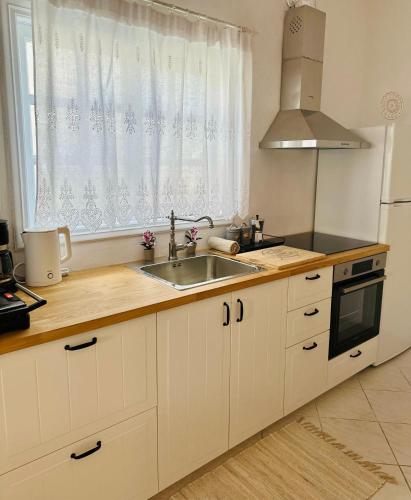 a kitchen with white cabinets and a sink and a window at Casa d' Irene fully equipped House in Koufonisia