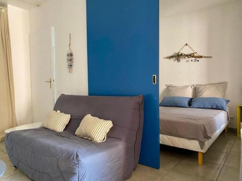 - une chambre avec un canapé et un mur bleu dans l'établissement Superbe appartement T2 en résidence avec piscine, à Saint-Cyprien