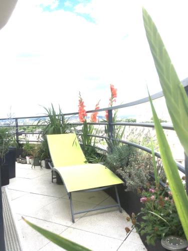 un banc jaune assis sur un balcon orné de plantes dans l'établissement Superbe ROOF-TOP avec vue 360°, à Colombes