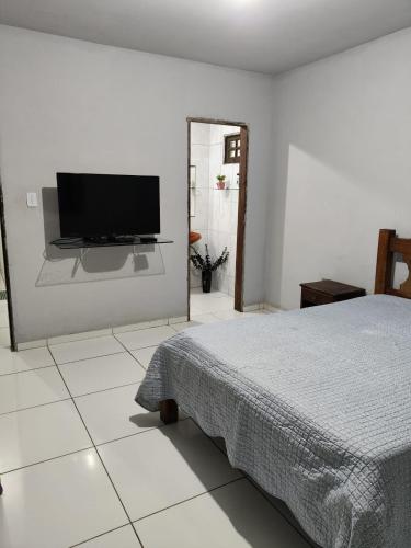 ein Schlafzimmer mit einem Bett und einem Flachbildfernseher in der Unterkunft Casa Festival de inverno Garanhuns in Garanhuns
