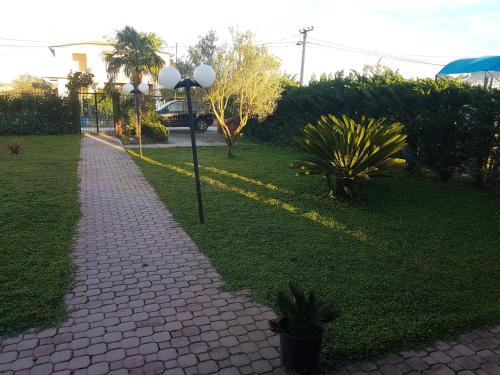 a brick sidewalk with two lights on the grass at Vila Elio Guest House in Divjakë