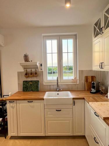 a kitchen with white cabinets and a sink and a window at Casa Katarina in Novalja