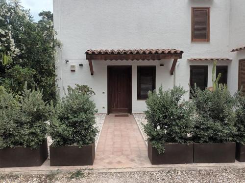 a white house with a door and some bushes at Villa Regina ai Faraglioni di Scopello in Scopello