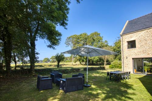 un patio avec tables, chaises et un parasol dans l'établissement Villa Piscine & Presqu'île, à Carnac