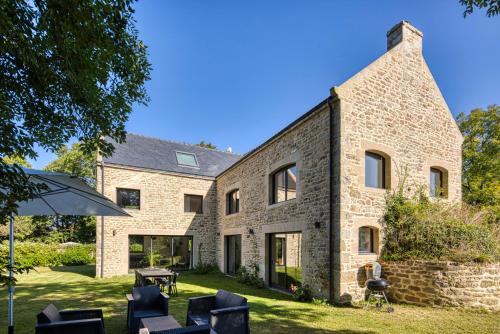 une vue extérieure d'une maison en pierre avec des chaises et un parasol dans l'établissement Villa Piscine & Presqu'île, à Carnac