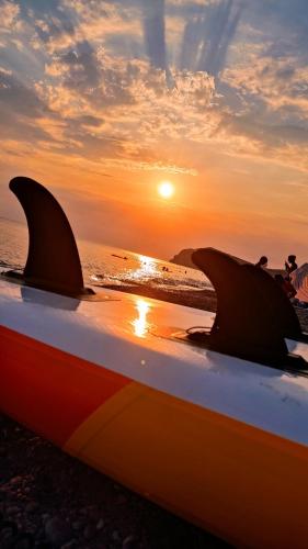 a surfboard on the beach with the sunset in the background at Chliara apartments by Tzalas in Skala Eresou