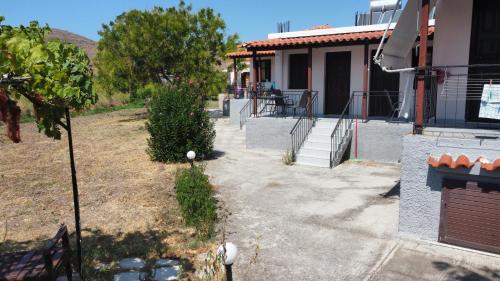 a house with a walkway next to a yard at Chliara apartments by Tzalas in Skala Eresou