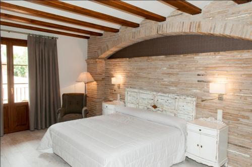 a bedroom with a white bed and a brick wall at Hotel Villa de Alquézar in Alquézar