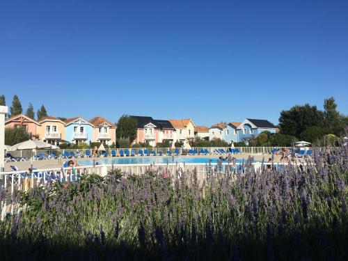 une plage avec une piscine, des maisons et des fleurs violettes dans l'établissement Maison calme sur golf, mer & campagne - Port Bourgenay, à Talmont-Saint-Hilaire