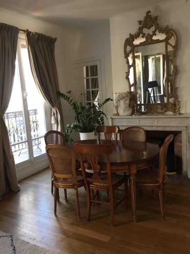 une salle à manger avec une table, des chaises et un miroir dans l'établissement Côté Arc de Triomphe, à Paris