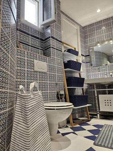 La salle de bains est pourvue de toilettes et de carrelage bleu et blanc. dans l'établissement Charmant Nice appartement 5 personnes people max, à Paris