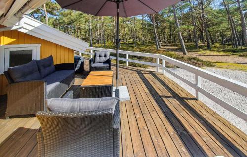 a wooden deck with chairs and an umbrella at Holiday Home Hejrevej Nexø Xii in Spidsegård