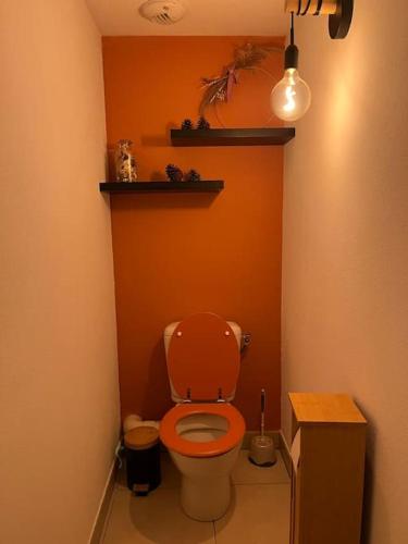 La salle de bains est pourvue de toilettes avec un mur orange. dans l'établissement Appartement entier, à Juvignac