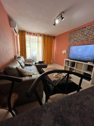 un salon avec un canapé et une télévision à écran plat dans l'établissement Appartement entier, à Juvignac