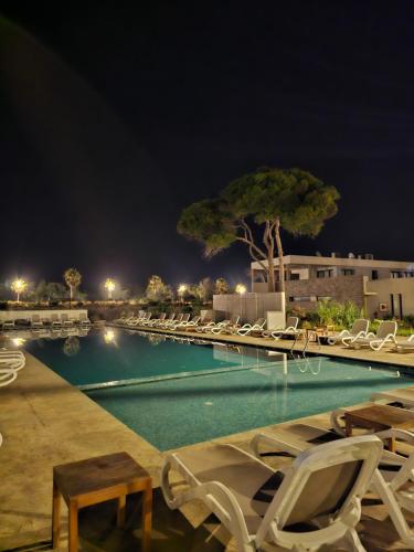 a swimming pool with lounge chairs at night at Appartement vue mer in Ajdir
