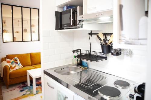 a kitchen with a sink and a couch at 2 Pièces Cosy - Mairie Des Lilas in Les Lilas