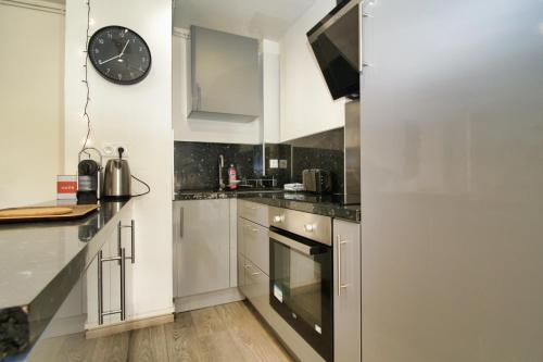 une cuisine avec des placards blancs et une horloge murale dans l'établissement Cosy Thiers - Hypercentre - Wifi, à Avignon