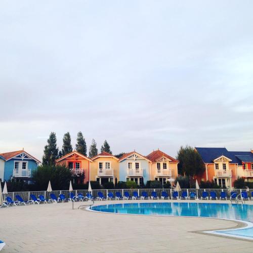 une piscine avec des chaises et des maisons en arrière-plan dans l'établissement Maison calme sur golf, mer & campagne - Port Bourgenay, à Talmont-Saint-Hilaire